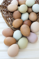 Fresh organic chickeneggs overflow out of basket on wooden backg