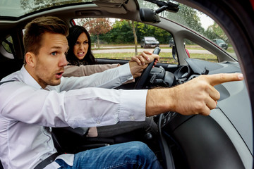 Paar im Auto streitet. Mann weist Frau auf Fahrfehler hin. Falsches Abbiegen durch Navigation