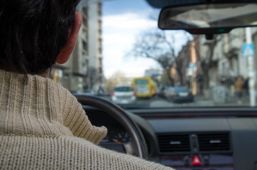 Young man drives his car through a busy street in a city