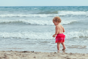 Fototapeta na wymiar Little cute happy girl bathes in sea, Italy, outdoor