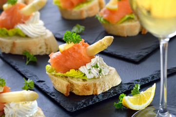 Canapes mit Lachs, weißem Spargel und Basilikum-Dill-Frischkäse, mit einem Glas Weißwein serviert - Canapes with smoked salmon, white asparagus and cream cheese with herbs, served with white wine