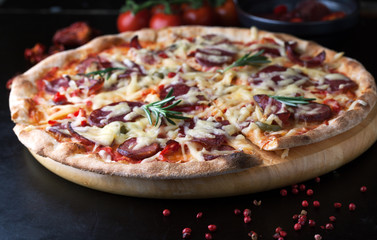 Delicious pizza with salami, tomatoes and hot peppers