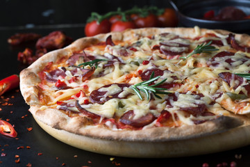 Delicious pizza with salami, tomatoes and hot peppers