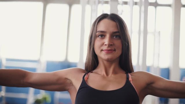 young woman flexing muscles on cable gym machine.