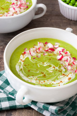 Peas cream with radishes on rustic wooden table
