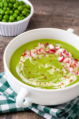 Peas cream with radishes on rustic wooden table
