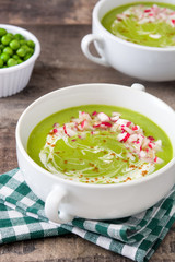 Peas cream with radishes on rustic wooden table
