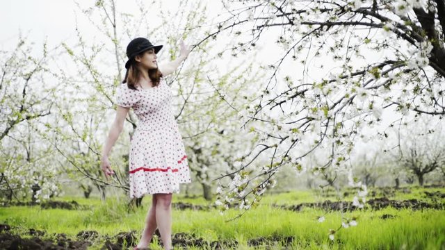 young woman dressed in retro style walking in blooming garden slow motion