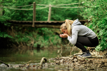 Woman drinking a fresh  water stream