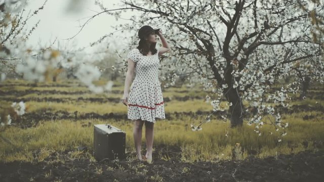 young woman dressed in retro style posing in blooming garden slow motion