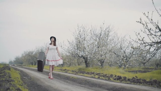 young woman dressed in retro style walks on the country road slow motion