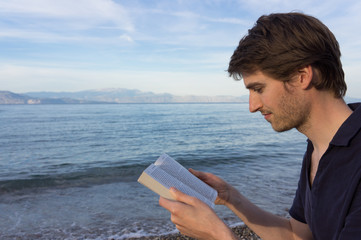 Young man reading at the beach