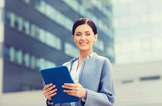 smiling business woman with tablet pc in city