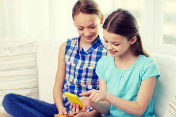 happy girls with smartphones sitting on sofa