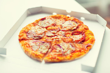 close up of pizza in paper box on table