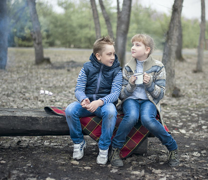 Two Kids Sitting On The Wooden Bench In The Park Cookout The Mar