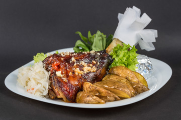 Grilled knuckle of pork, vegetables and potate on white plate