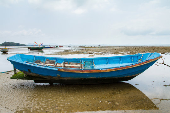 An old fishing boat moored beached on the beach at low tide.