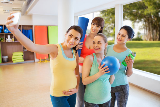 pregnant women taking selfie by smartphone in gym