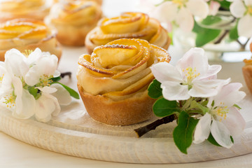 Obraz na płótnie Canvas Homemade apple rose cakes decorated apple blossom on white wooden desk
