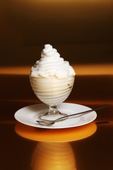 Dessert with creamy cream in glass vase on brown background
