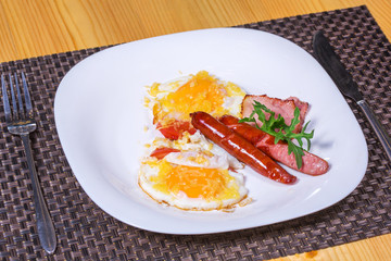 Cooked breakfast with fried eggs, sausages, bacon and cheese