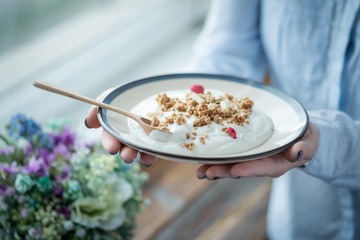 A cup of fresh yogurt in woman's hands