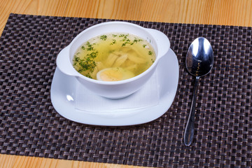 Chicken broth with a half cooked egg and greens 