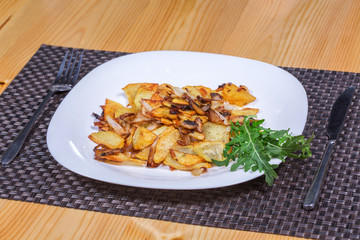 Roasted potato and mushrooms with greens in white plate 