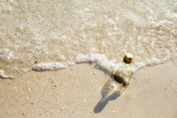Empty glass bottle washed up as rubbish on a beach, garbage on b