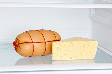 Appetizing sausage and cheese on refrigerator shelf