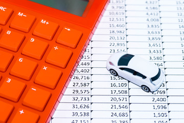 Image of auto related expense, with calculator, spreadsheet, and toy car