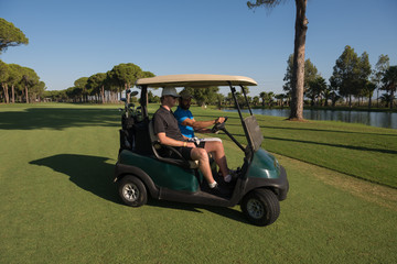 golf players driving cart at course