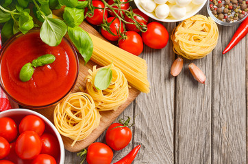 Pasta, vegetables, herbs and spices for Italian food on the rustic wooden table, top view, copy space