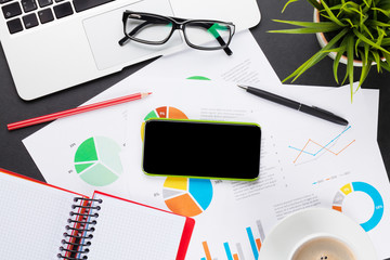 Office table with laptop, coffee, smartphone and reports