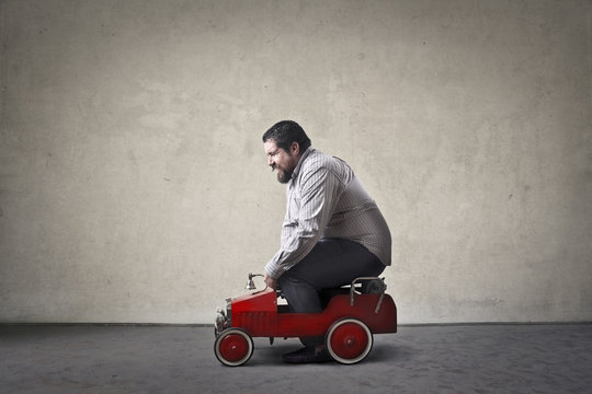 Chubby man driving toy car