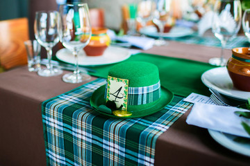 Green hat on a checkered tablecloth. Serving wedding table