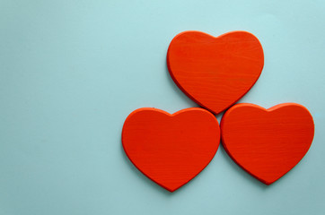 Tris di cuori in legno dipinti di rosso su sfondo azzurro senza scritta