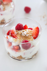 Homemade healthy dessert in a glass with yogurt, fresh fruits and cookies for breakfast, closeup.
