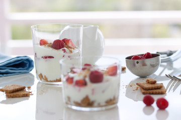 Homemade healthy dessert in glass with yogurt, fresh fruits and cookies for breakfast, closeup.