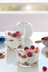 Homemade healthy dessert in a glass with yogurt, fresh fruits and cookies for breakfast, closeup.