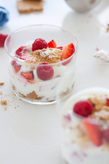 Homemade healthy dessert in a glass with yogurt, fresh fruits and cookies for breakfast, closeup.