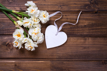 Fototapeta premium White narcissus flowers and decorative heart on brown wooden