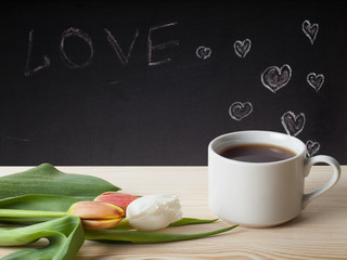 Romantic theme on a chalkboard behind a wooden table with cup of