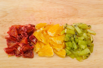 Cut slices of red and orange orange and kiwi closeup on cutting Board