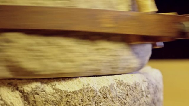 Close-up shot of historic hand-driven millstone grinding wheat