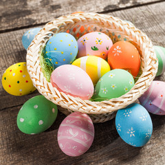 Easter eggs in nest on color wooden background