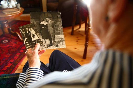 senior/ elderly woman looking at her wedding photo's 