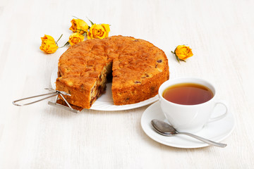 Homemade cake with a piece cut off and cup of tea