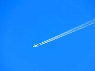 Airplane with chemtrails on blue sky